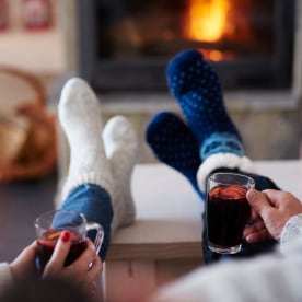 Mature couple with hot drinks in living room at the fireplace