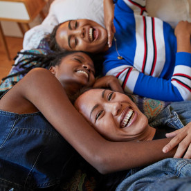 Young female friends lying on bed at home